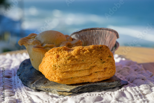 Portugeese food  oven baked chicken pie empada de frango and codfish croquette pastais de bacalhau  served outdoor with view on blue Atlantic ocean near Sintra in Lisbon area  Portugal