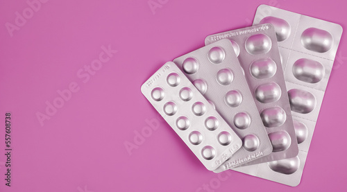 pile of tablets pill in silver blister packaging on pink background. Aluminium foil blister pack. Pharmacy products. Medicine pills and drugs close up. Pills background. photo