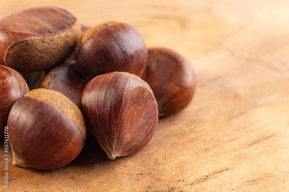 A Pile of Raw and Whole Chestnuts on a Wooden Table A Pile of Raw and Whole Chestnuts on a Wooden Table