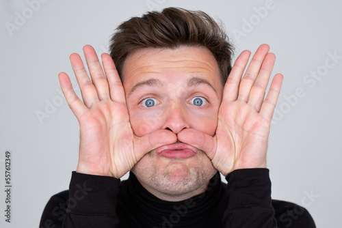 young Caucasian man grimacing, having stupid and ridiculous facial expression. photo