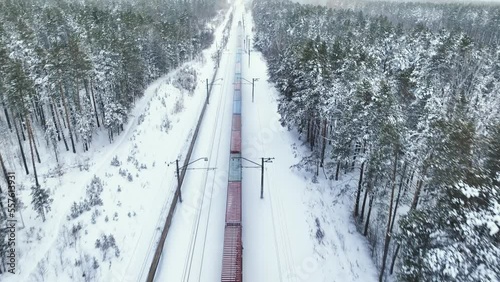 Freight train rides in the middle of a winter snowy forest. Aerial view
