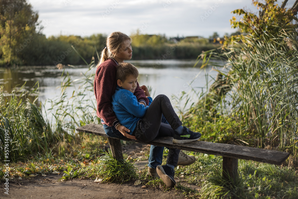 Mother hugging boy outdoors on the bench. Mother kissing son in the park. Precious moments between mom and son Mother hugging boy outdoors on the bench. Mother kissing son in the park. Precious moments between mom and son