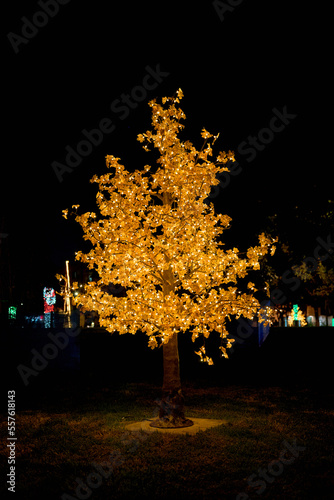 plastic tree with yellow light bulbs in the middle of the park. christmas decoration at Alcala park in Bogota in Colombia. christmas lights on tree. plastic tree leaves glowing 