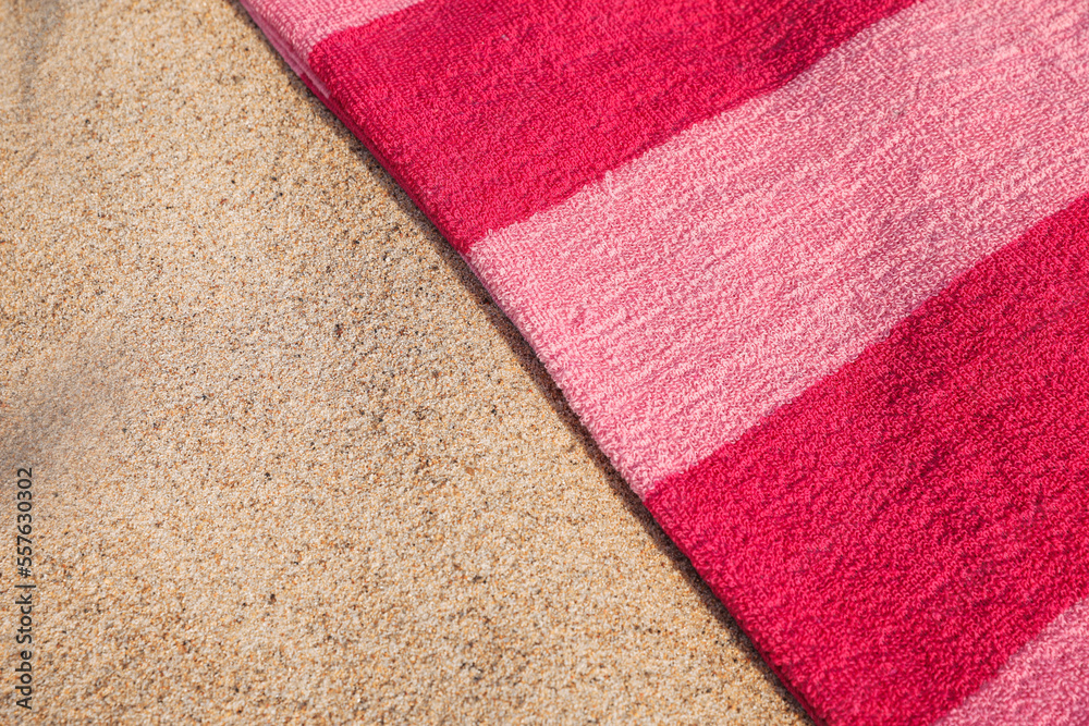 Fototapeta premium Soft pink beach towel on sand, above view. Space for text