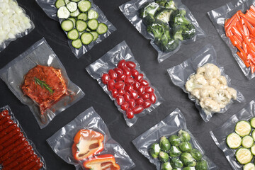 Flat lay composition of different food in vacuum packings on dark grey table