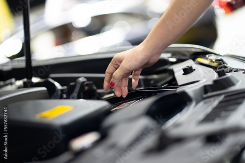 Woman fixing parts while opening car hood repairing engine and inspecting engine