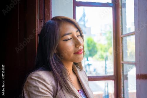 business brunette woman relaxed and happy breathing fresh air in a window