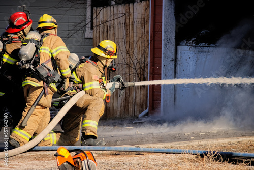Firefighter uses a hose to battle a house fire