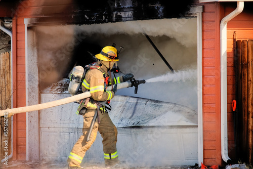 Firefighter uses a hose to battle a house fire