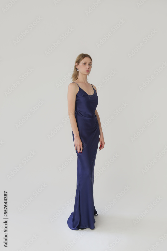 Woman in dark blue silk satin camisole dress, studio shot.	
