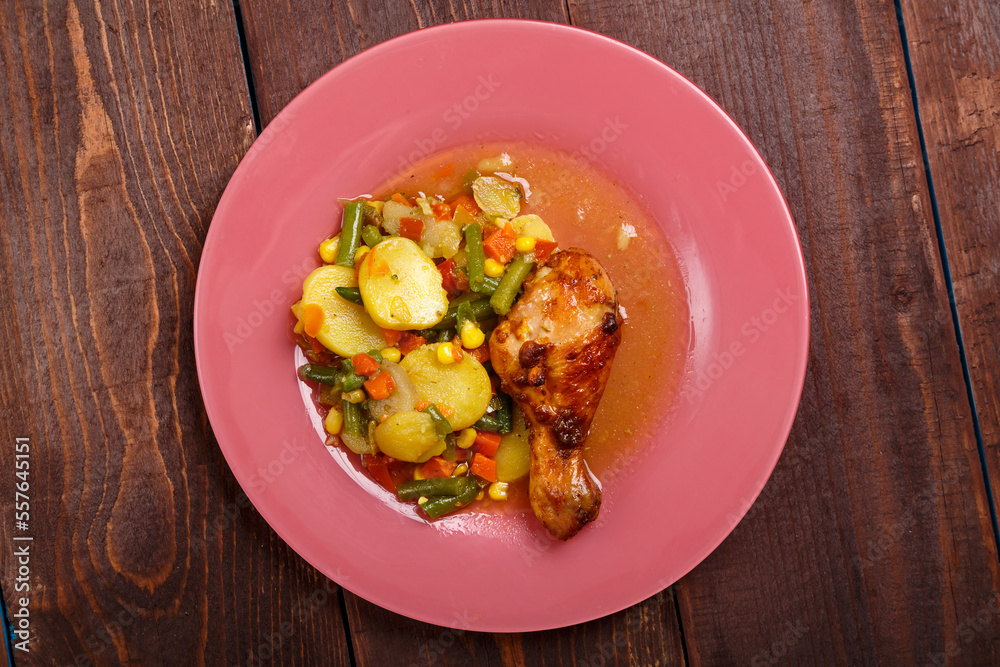 Baked chicken drumstick with vegetables potatoes green beans in sauce and spices on a wooden table. Baked chicken drumstick with vegetables potatoes green beans in sauce and spices on a wooden table.
