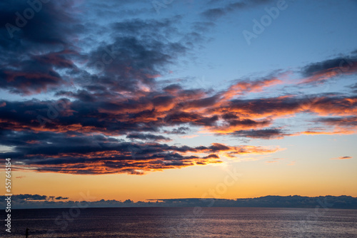 日の出の太陽の照らせれオレンジ色に輝く雲と空 © Kazcamera