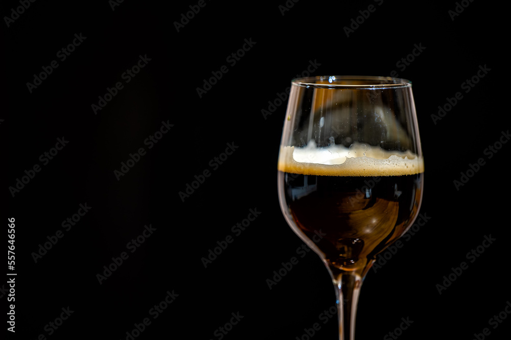 Dark beer in a glass on a black background. Dark beer in a glass on a black background.
