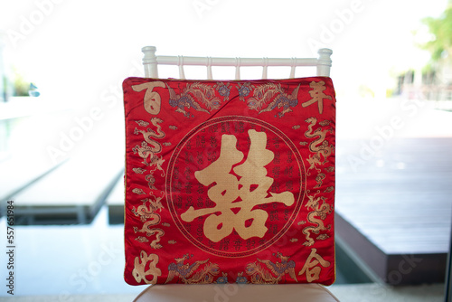 1 red pillow for the red Chinese wedding ceremony There are auspicious characters and dragon patterns written on the pillow. sits on a chair.