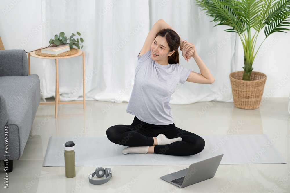 Young asian woman attractive exercises workout at home and watching Online sports tutorials over laptop