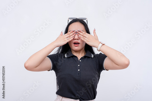 A young woman covers her eyes from a scary sight. Expressing aversion. Isolated on a white background.