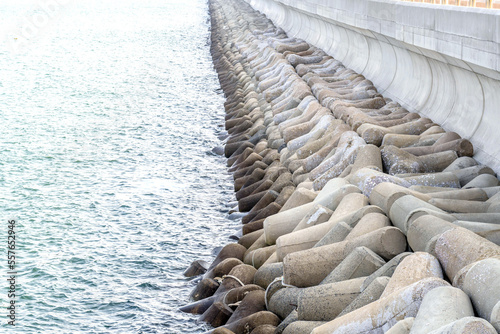 Rows of tetrapods lined against concrete pier at seaport.