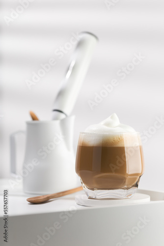 Cappuccino in a glass cup on a white wooden table, Coffee and froth milk.