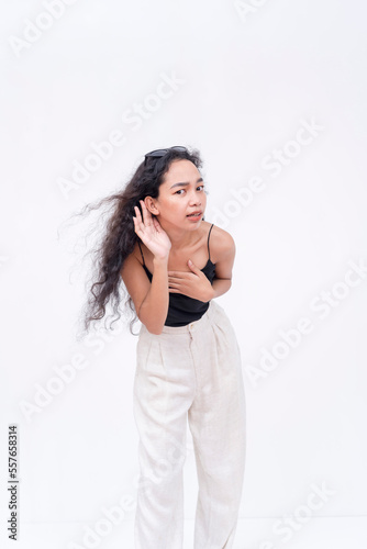 A shocked young woman in disbelief and incredulity. Leaning forward to hear better and double check. Isolated on a white background.