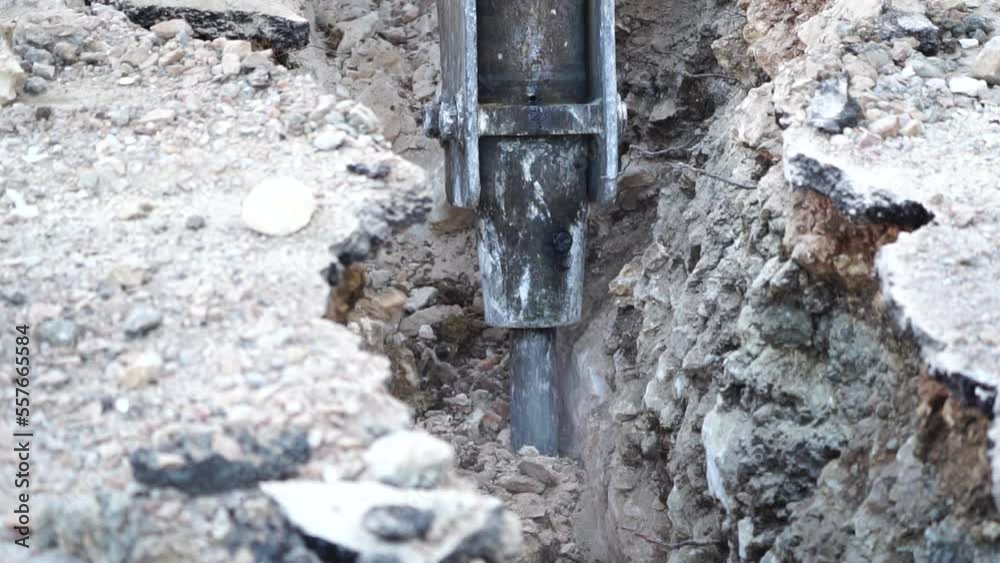 Destruction of solid soil rock with pneumatic jackhammer excavator