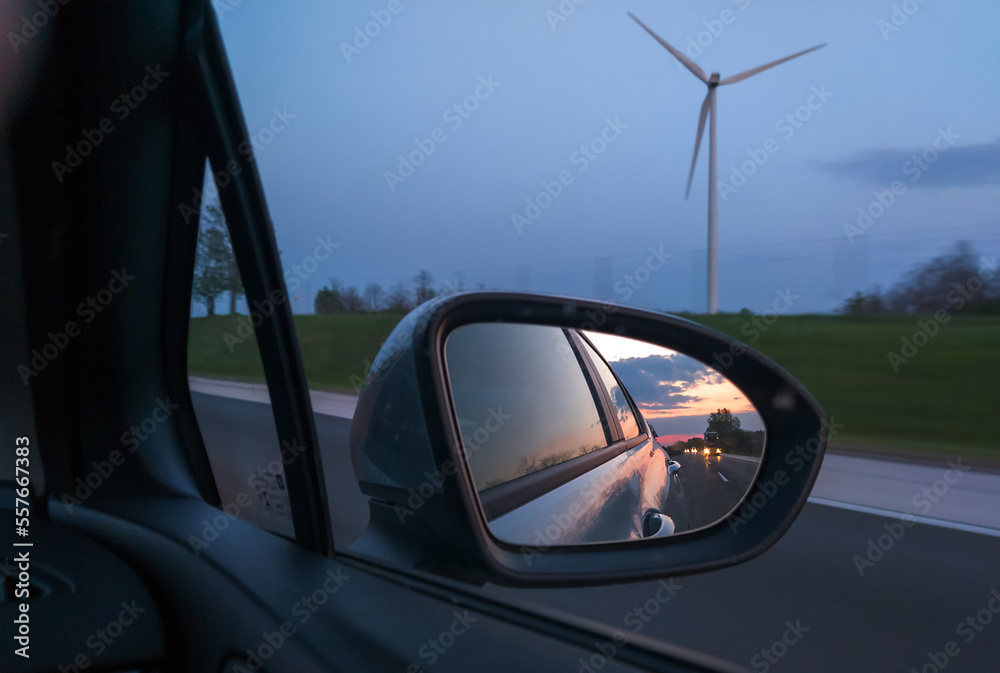 View of wind power plant from car driving on a road