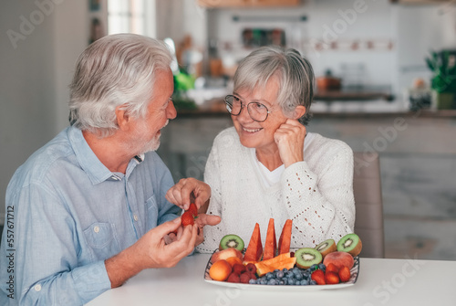 Happy beautiful senior couple at home having breack or breakfast getting ready to eat a plate of fresh seasonal fruit, healthy eating concept photo
