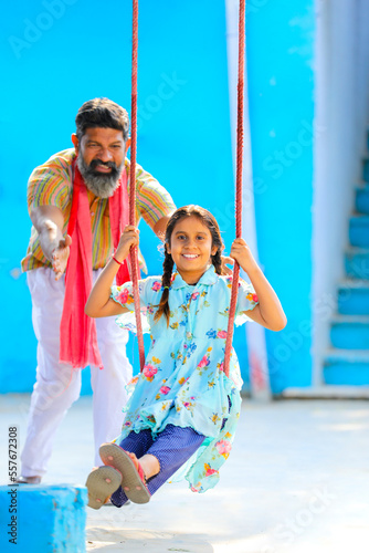 Indian farmer swinging to her daughter at home.