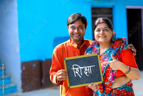 Indian rural couple showing slate. Shiksha word in marathi calligraphy on slate