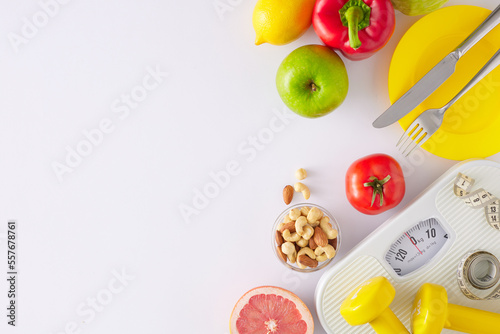 Proper nutrition concept. Flat lay composition made of scales, dumbbells, tape measure, plate with cutlery, vegetables, fruits and nuts on white background with copy space. Slimming idea.