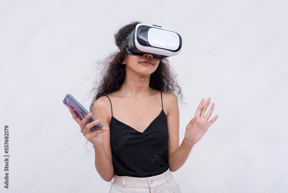 A young asian woman explores a VR environment via a virtual reality headset connected to her cellphone app. Isolated on a white backdrop. A young asian woman explores a VR environment via a virtual reality headset connected to her cellphone app. Isolated on a white backdrop.