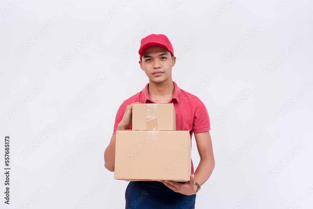 A handsome asian delivery man, carrying two boxes. Wearing a matching red cap and polo shirt. A courier handling and delivering parcels. Isolated on a white background. A handsome asian delivery man, carrying two boxes. Wearing a matching red cap and polo shirt. A courier handling and delivering parcels. Isolated on a white background.
