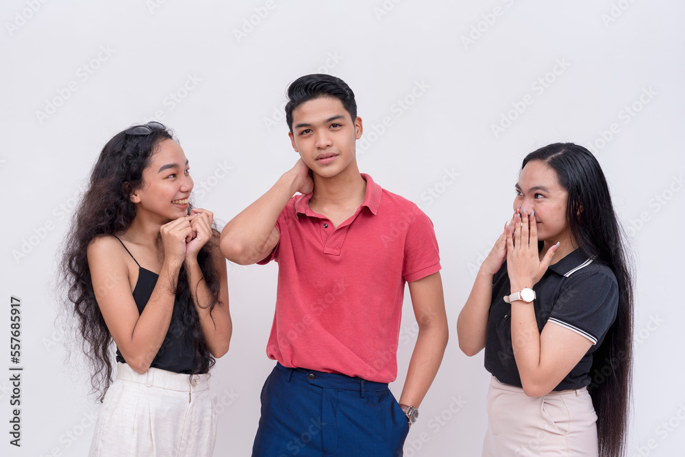 A popular young man feeling handsome and full of himself after getting the attention of two enamored women. Isolated on a white background. A popular young man feeling handsome and full of himself after getting the attention of two enamored women. Isolated on a white background.