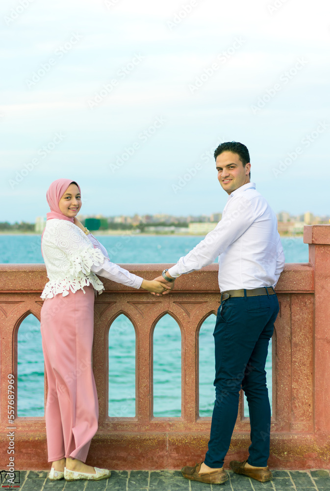 Young couple in love standing on the beach, enjoying sunset ocean. Close head horizontal portrait.