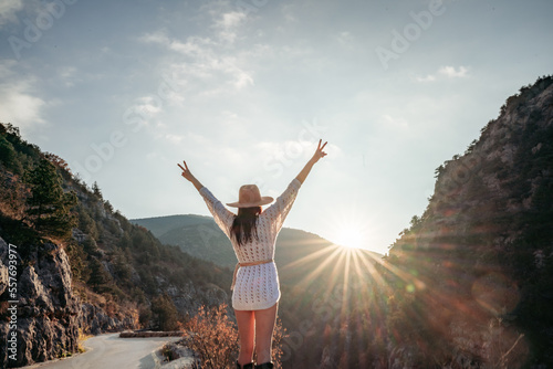 Traveler woman in brown hat and white sweater looking at amazing mountains and forest, wanderlust travel concept, atmospheric epic moment
