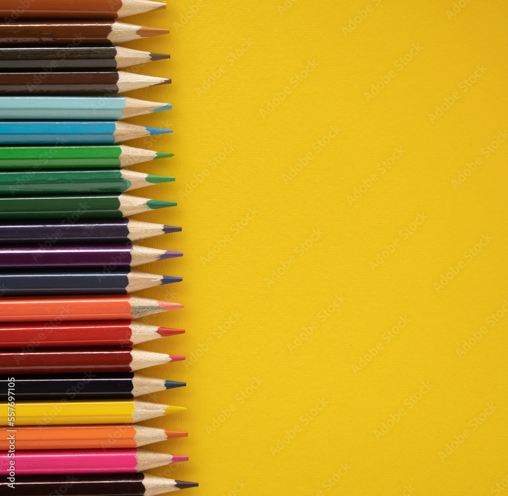 school pencils of various colors stacked in a row on.yellow background school pencils of various colors stacked in a row on.yellow background
