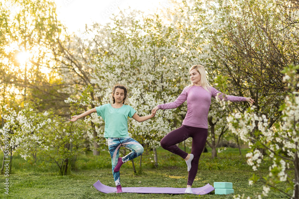 two young women and a little girl in their garden doing yoga