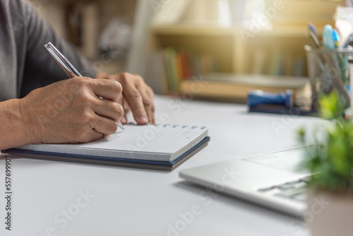 Woman hands with pen writing on notebook in the office.learning, education and work.writes goals, plans, make to do and wish list on desk.