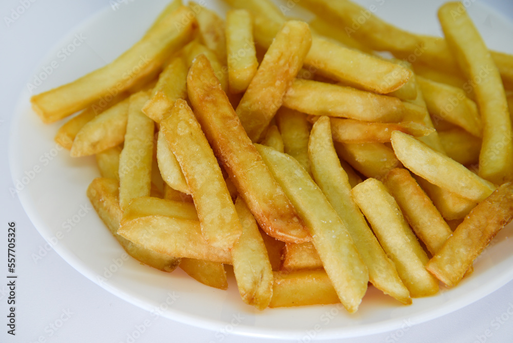 Yellow delicious French fries in white dishes. Fast food on a plate. Fried potatoes. Toasted potato slices on a white background. Yellow delicious French fries in white dishes. Fast food on a plate. Fried potatoes. Toasted potato slices on a white background.
