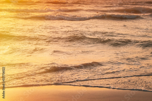 Sunset above sea. Riplpe sea ocean water surface with small waves. Ocean water foam splash washing sandy beach.