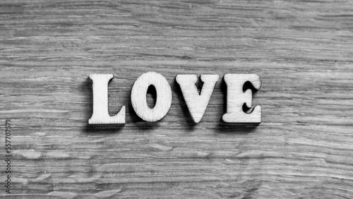 Love - word inscription of 3D wooden letters on the wood textured board background. Expression of romantic theme or Valentines Day. Rustic style inscription. Black and white image.