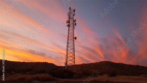 A communications tower with colorful sunset clouds photo