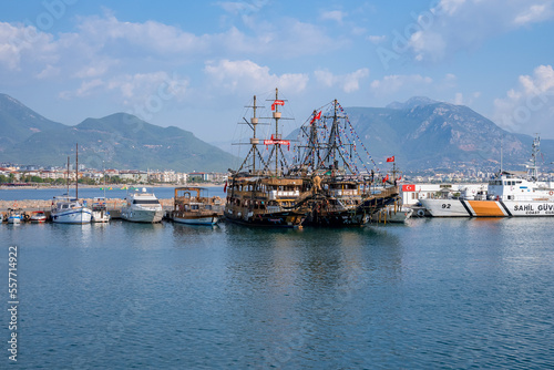 Side, Turkey. October 10, 2022. Yachts and pirate ships moored at harbor with scenic view of sea and mountains under cloudy sky in the background during sunny day