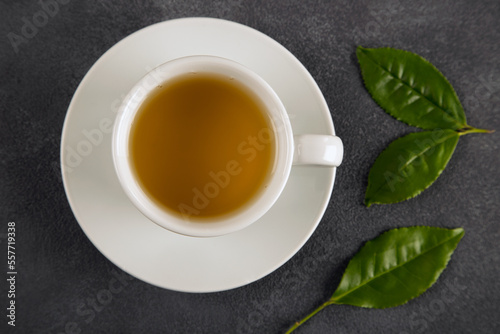 Tea leaves with a white cup of green tea,on black background