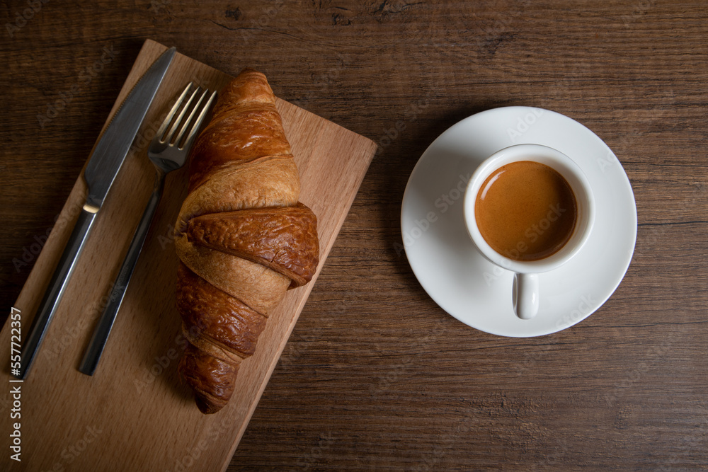 Croissant with espresso in white cup on wooden background
Croissant with espresso in white cup on wooden background