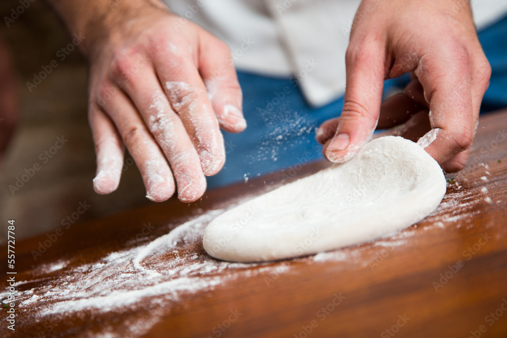 Preparing the dough for a Neapolitan pizza with tomato and cheese.