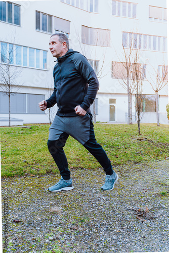 Middle-aged man in tracksuit doing jog in morning