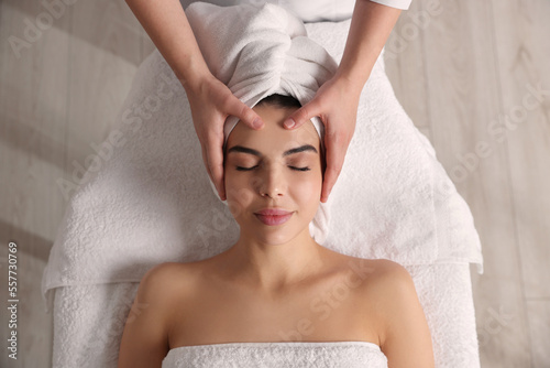 Beautiful woman receiving facial massage in beauty salon, closeup. Top view