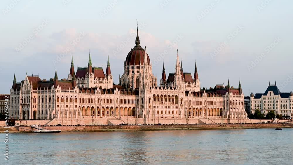 Budapest, Hungary, August 2022. Stunning three-quarter view of the parliament from the Danube river side. The yellow light of late afternoon warms the facade. Budapest, Hungary, August 2022. Stunning three-quarter view of the parliament from the Danube river side. The yellow light of late afternoon warms the facade.