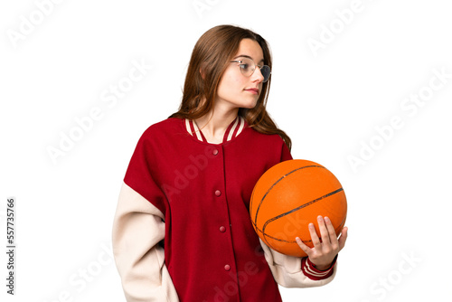 Teenager girl playing basketball over isolated chroma key background looking to the side