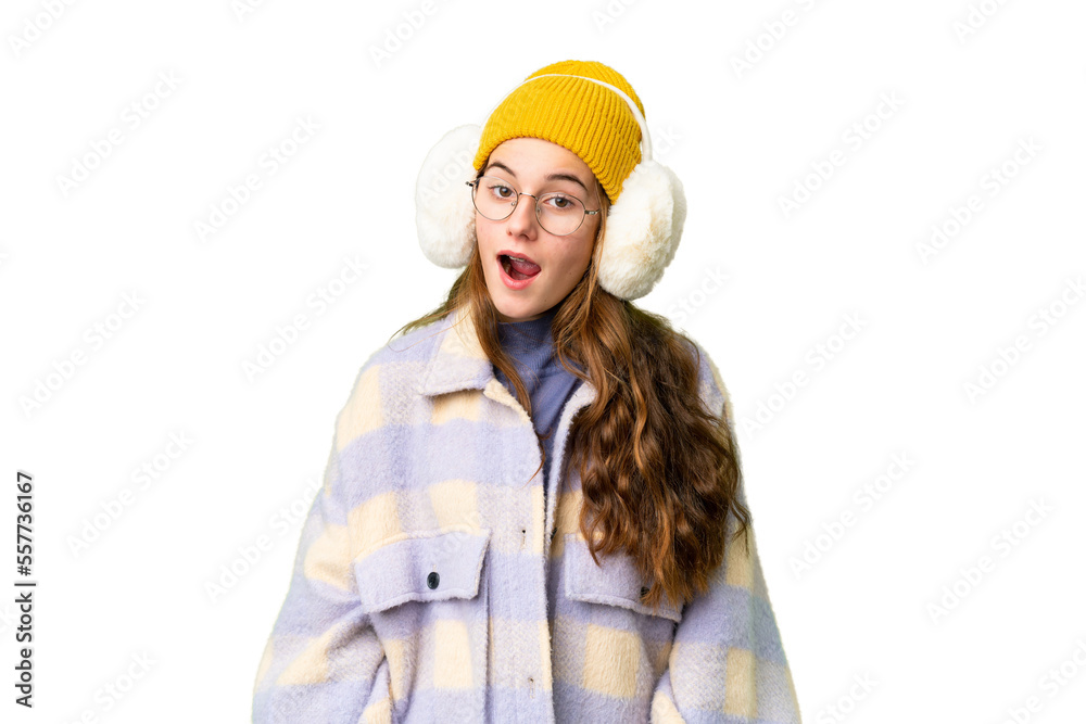 Teenager girl wearing winter muffs over isolated chroma key background with surprise facial expression Teenager girl wearing winter muffs over isolated chroma key background with surprise facial expression